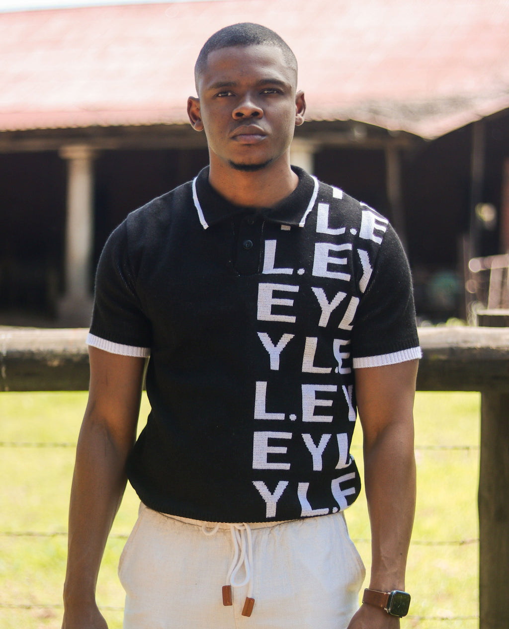 Man wearing a black polo shirt with white text outdoors
